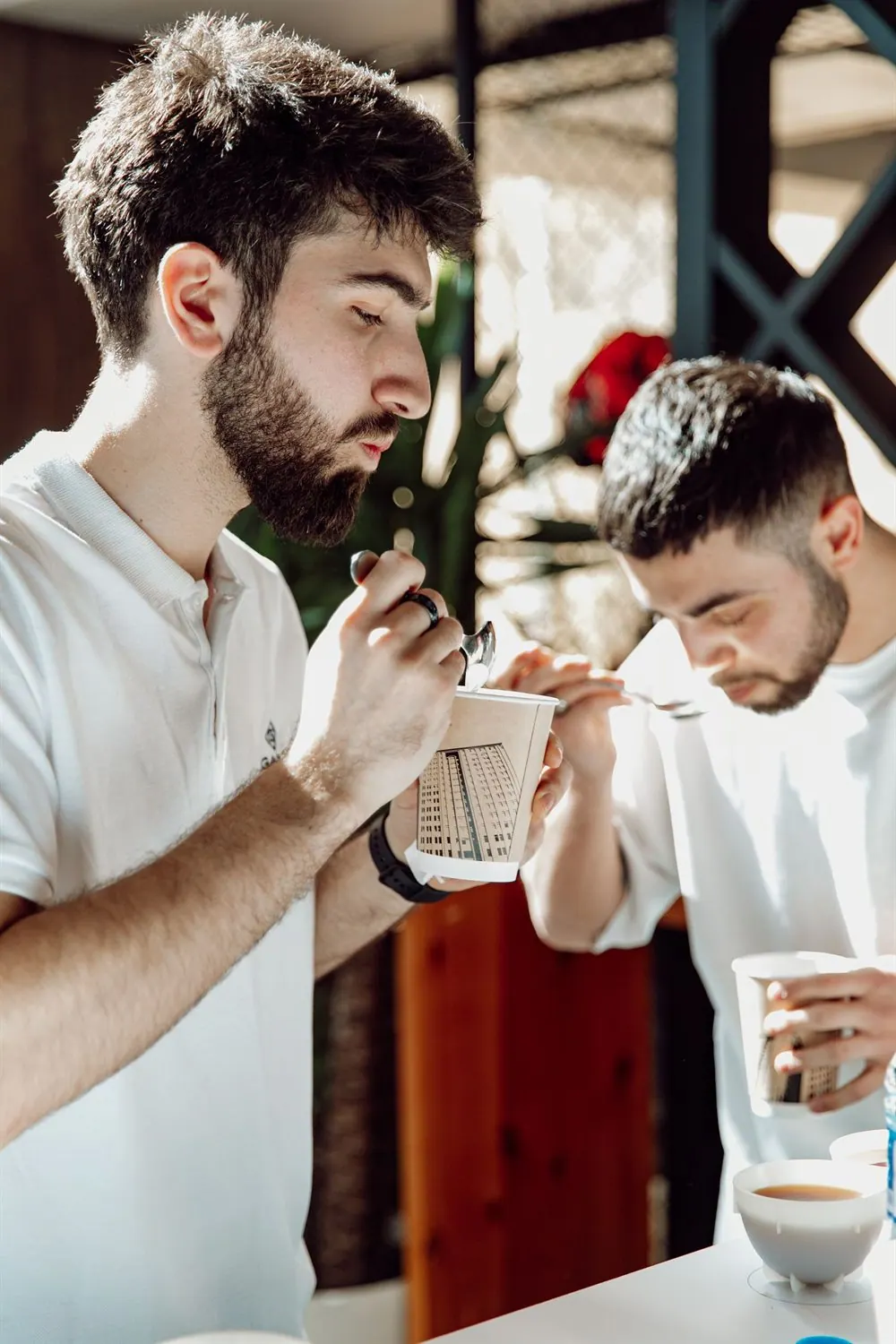 Dos personas probando café de vasos de papel en una mesa